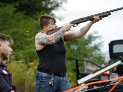 In this Oct. 8, 2017, photo, Jake Allen, left, watches as Lore McSpadden fires at a clay target he released during a training session for the Trigger Warning Queer & Trans Gun Club in Victor, N.Y. McSpadden never touched a gun before the gun club started this past year. (AP Photo/Adrian Kraus)