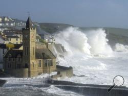 Waves break around the church in the harbour at Porthleven, Cornwall southwestern England, as the remnants of Hurricane Ophelia begins to hit parts of Britain and Ireland. Ireland's meteorological service is predicting wind gusts of 120 kph to 150 kph (75 mph to 93 mph), sparking fears of travel chaos. Some flights have been cancelled, and aviation officials are warning travelers to check the latest information before going to the airport Monday. (Ben Birchall/PA via AP)