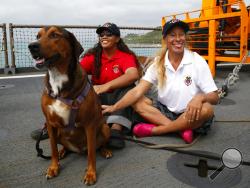 Jennifer Appel, right, and Tasha Fuiava sit with their dogs on the deck of the USS Ashland Monday, Oct. 30, 2017, at White Beach Naval Facility in Okinawa, Japan. The U.S. Navy ship arrived at the American Navy base, five days after it picked up the women and their two dogs from their storm-damaged sailboat, 900 miles southeast of Japan. (AP Photo/Koji Ueda)