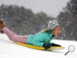 Finley Bork, 7, uses a boogie board, typically used on the beach, for sledding down a hill on a golf course at the Isle of Palms, S.C., Wednesday, Jan. 3, 2018. A brutal winter storm smacked the coastal Southeast with a rare blast of snow and ice Wednesday, hitting parts of Florida, Georgia and South Carolina with their heaviest snowfall in nearly three decades. (AP Photo/Mic Smith)