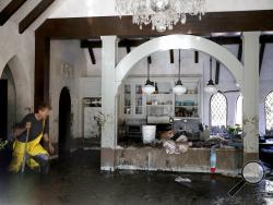 Bill Asher walks through mud in his home damaged by storms in Montecito, Calif., Thursday, Jan. 11, 2018. Rescue workers slogged through knee-deep ooze and used long poles to probe for bodies Thursday as the search dragged on for victims of the mudslides that slammed this wealthy coastal town. (AP Photo/Marcio Jose Sanchez)