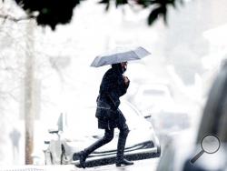 A woman walks through Fort Sanders during an afternoon snowfall in Knoxville, Tenn., Tuesday, Jan. 16, 2018. (Calvin Mattheis/Knoxville News Sentinel via AP)