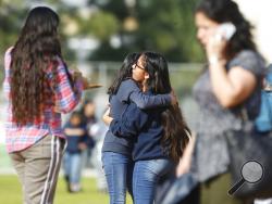Students hug as people pick up students after a shooting at the Salvador B. Castro Middle School near downtown Los Angeles Thursday, Feb. 1, 2018. A girl opened fire Thursday in a middle school classroom on Thursday, authorities said. (AP Photo/Damian Dovarganes)