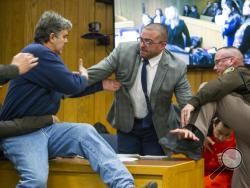 Randall Margraves, father of three victims of Larry Nassar , left, lunges at Nassar, bottom right, Friday, Feb. 2, 2018, in Eaton County Circuit Court in Charlotte, Mich. The incident came during the third and final sentencing hearing for Nassar on sexual abuse charges. The charges in this case focus on his work with Twistars, an elite Michigan gymnastics club. (Cory Morse/The Grand Rapids Press via AP)