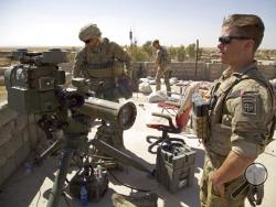 FILE - In this Aug. 20, 2017 file photo, U.S. Army soldiers stands next to a guided-missile launcher, a few miles from the frontline, in the village of Abu Ghaddur, east of Tal Afar, Iraq. American troops have started to draw down from Iraq following Baghdad’s declaration of victory over the Islamic State group last year, according to western contractors at a U.S.-led coalition base in Iraq. (AP Photo/Balint Szlanko, File)