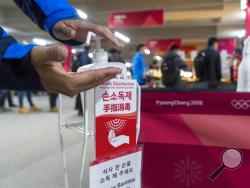 A man sanitizes his hands at the entrance to the media cafeteria in Gangneung, South Korea, Wednesday, Feb. 7, 2018. South Korean authorities deployed 900 military personnel at the Pyeongchang Olympics on Tuesday after the security force was depleted by an outbreak of norovirus. (Paul Chiasson/The Canadian Press via AP)