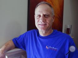 In this Feb. 16, 2018, photo, Andy Cilek poses with a Tea Party shirt at his home in Eden Prairie, Minn. Cilek was one of two voters who defied elections officials after he was asked to cover up a tea-party shirt and button. A Minnesota law that bars voters from wearing political hats, T-shirts, buttons and other apparel to the polls is about to get a look from the Supreme Court. (AP Photo/Jim Mone)