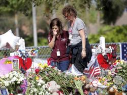 Margarita Lasalle, a bookkeeper and Joellen Berman, a guidance data specialist, look at a memorial Friday, Feb. 23, 2018 as teachers and school administrators returned to Marjory Stoneman Douglas High School for the first time since 17 victims were killed in a mass shooting at the school, in Parkland, Fla. (Mike Stocker/South Florida Sun-Sentinel via AP)
