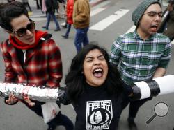 Demonstrators, including, Valeria Suarez, center, and Gerardo Gomez, right, yell slogans as they block an intersection outside of the Immigration and Customs Enforcement offices Wednesday, Feb. 28, 2018, in San Francisco. A top immigration official said Wednesday that about 800 people living illegally in Northern California were able to avoid arrest because of a weekend warning that Oakland Mayor Libby Schaaf put on Twitter.(AP Photo/Marcio Jose Sanchez)