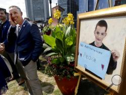 FILE - In this Aug. 16, 2017 file photo, Bill Richard, second from left, stands beside a painting of his son Martin Richard, the youngest person killed in the Boston Marathon bombing, at the conclusion of groundbreaking ceremonies for a Boston park named in Martin's honor. Besides the park, the family has also set up a foundation in Martin's memory. (AP Photo/Steven Senne, File)