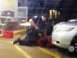 FILE - In this July 5, 2016 image made from video provided by Arthur Reed, Alton Sterling is restrained by two Baton Rouge police officers, one holding a gun, outside a convenience store in Baton Rouge, La. Moments later, one of the officers shot and killed Sterling, a black man who had been selling CDs outside the store, while he was on the ground. The investigation of the deadly police shooting that inflamed racial tensions in Louisiana’s capital city has ended without criminal charges against two white o