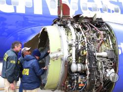 National Transportation Safety Board investigators examine damage to the engine of the Southwest Airlines plane that made an emergency landing at Philadelphia International Airport in Philadelphia on Tuesday, April 17, 2018. The Southwest Airlines jet blew the engine at 32,000 feet and got hit by shrapnel that smashed a window, setting off a desperate scramble by passengers to save a woman from getting sucked out. She later died, and seven others were injured. (NTSB via AP)