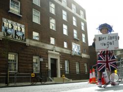 FILE - In this Friday, April 24, 2015 file photo, Terry Hutt poses for the media with a sign that reads 'Not Long to Go' as he waits with other royal fans, outside the Lindo wing at St Mary's Hospital in London. Kensington Palace says Prince William's wife, the Duchess of Cambridge has entered a London hospital to give birth to the couple's third child. The former Kate Middleton traveled by car on Monday, April 23, 2018 to the private Lindo Wing of St. Mary's Hospital in central London. The palace says she 