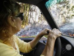 In this Sunday, May 6, 2018, photo, Leilani Estates resident Lucina Aquilina drives near lava on Luana Street in the Leilani Estates subdivision, in Pahoa, Hawaii. Hawaii's Kilauea volcano has destroyed homes and spewed lava hundreds of feet into the air, leaving evacuated residents unsure how long they might be displaced. (Jamm Aquino/Honolulu Star-Advertiser via AP)