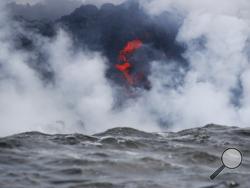 Lava flows into the ocean near Pahoa, Hawaii, Sunday, May 20, 2018. Kilauea volcano that is oozing, spewing and exploding on Hawaii's Big Island has gotten more hazardous in recent days, with rivers of molten rock pouring into the ocean Sunday and flying lava causing the first major injury. (AP Photo/Jae C. Hong)