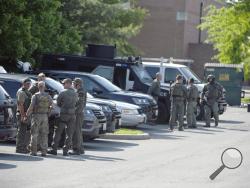 Tactical police stage in a Safeway parking lot on Belair Road near Chapel Road in response to the death of a Baltimore County police officer in Perry Hall, Md., May 21, 2018. Rifle-toting police swarmed into the Baltimore suburb where a female officer was fatally injured Monday, searching for suspects believed to be armed after witnesses reported hearing a pop and seeing the officer run over by a Jeep. (Jerry Jackson/The Baltimore Sun via AP)
