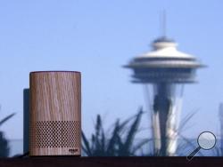 FILE - In this Sept. 27, 2017, file photo, an Amazon Echo device sits on a balcony outside an Amazon office as the Space Needle is reflected in windows behind it following a program announcing several new Amazon products by the company, in Seattle. Amazon says an "unlikely" string of events prompted its Echo personal assistant device to record a Portland, Ore., family's private conversation and then send the recording to an acquaintance in Seattle. (AP Photo/Elaine Thompson, File)