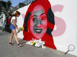 A woman places flowers by a mural showing Savita Halappanavar, a 31-year-old Indian dentist who had sought and been denied an abortion before she died after a miscarriage in a Galway hospital, with the word YES over it, in Dublin, Ireland, on the day of a referendum on the 8th amendment of the constitution. 