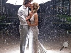 In this Saturday, May 26, 2018, photo provided by the Florida Keys News Bureau, Hannibal and Emily Baldwin pose for a wedding photo under an umbrella outside the Casa Marina Resort in Key West, Fla. The Tampa, Fla., couple had planned an outdoor wedding, but the evening ceremony and reception were moved inside due to rain bands emanating from Subtropical Storm Alberto. (Bob Care/Florida Keys News Bureau via AP)