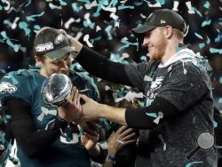FILE - In this Feb. 4, 2018 photo, Philadelphia Eagles quarterback Carson Wentz, right, hands the Vincent Lombardi trophy to Nick Foles after winning the NFL Super Bowl 52 football game against the New England Patriots in Minneapolis. The Eagles won 41-33. President Donald Trump has called off a visit by the Philadelphia Eagles to the White House Tuesday due to the dispute over whether NFL players must stand during the playing of the national anthem. Trump says in a statement that some members of the Super 