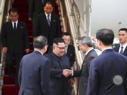 In this photo released by the Ministry of Communications and Information of Singapore, North Korean leader Kim Jong Un, center left, is greeted by Singapore Minister for Foreign Affairs Dr. Vivian Balakrishnan at the Changi International Airport, Sunday, June 10, 2018, in Singapore, ahead of a summit with U.S. President Donald Trump. (Ministry of Communications and Information Singapore via AP)