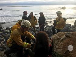 In this Friday, July 13, 2018, photo posted on the Monterey County, Calif., Sheriff's Office Twitter feed, authorities tend to Angela Hernandez, foreground center, after she was rescued, in Morro Bay, Calif. Authorities say a couple on a camping trip came upon Hernandez, from Oregon, who had been missing since July 6, after her car went over a cliff in coastal California. (Monterey County Sheriff's Office via AP)