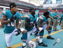 FILE - In this Sunday, Oct. 23, 2016, file photo, Miami Dolphins wide receiver Kenny Stills (10), free safety Michael Thomas (31) and defensive back Chris Culliver (29) kneel during the National Anthem before the first half of an NFL football game against the Buffalo Bills in Miami Gardens, Fla. Miami Dolphins players who protest on the field during the national anthem this season could be suspended for up to four games under a new team policy issued to players this week. The policy obtained by The Associat