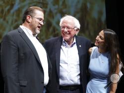 Kansas congressional candidate James Thompson, left, U.S Sen. Bernie Sanders, I-Vt., and Alexandria Ocasio-Cortez, a Democratic congressional candidate from New York, stand together on stage after a rally, Friday, July 20, 2018, in Wichita, Kan. (Jaime Green/The Wichita Eagle via AP)