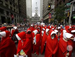Protesters, in view of City Hall, center, dressed as characters from "The Handmaid's Tale," demonstrate against Vice President Mike Pence's visit to the Union League in Philadelphia, Monday, July 23, 2018. (AP Photo/Matt Rourke)