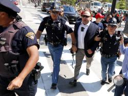 FILE - In this Tuesday, July 19, 2016 file photo, Alex Jones, center right, is escorted by police out of a crowd of protesters outside the Republican convention in Cleveland. Facebook says it has taken down four pages belonging to conspiracy theorist Alex Jones for violating its hate speech and bullying policies. The social media giant said in a statement Monday, Aug. 6, 2018 that it also blocked Jones' account for 30 days because he repeatedly posted content that broke its rules. (AP Photo/John Minchillo, 