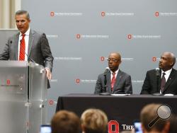 Ohio State football coach Urban Meyer, left, makes a statement during a news conference as university President Michael Drake, center, and athletic director Gene Smith listen in Columbus, Ohio, Wednesday, Aug. 22, 2018. Ohio State suspended Meyer on Wednesday for three games for mishandling domestic violence accusations, punishing one of the sport's most prominent leaders for keeping an assistant on staff for several years after the coach's wife accused him of abuse. Gene Smith was suspended from Aug. 31 th