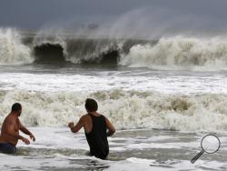 John Cunningham, left, and Hunter Shows, right, watch the waves crash from Tropical Storm Gordon on Tuesday, Sept. 4, 2018, in Dauphin Island, Ala. (AP Photo/Dan Anderson)