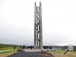 FILE - In this Sept. 9, 2018 file photo, people attending the dedication stand around the 93-foot tall Tower of Voices at the Flight 93 National Memorial in Shanksville, Pa., where the tower contains 40 wind chimes representing the 40 people that perished in the crash of Flight 93 in the terrorist attacks of Sept. 11, 2001. Thousands of victims' relatives, survivors, rescuers and others are expected at Tuesday's Sept 11 Anniversary ceremony at the World Trade Center. President Donald Trump and first lady Me