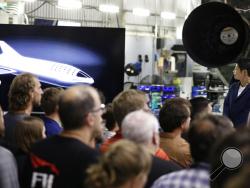 Japanese billionaire Yusaku Maezawa, right, looks at a monitor showing the BFR spacecraft after SpaceX founder and chief executive Elon Musk announced him as the first scheduled private passenger on a trip around the moon, Monday, Sept. 17, 2018, in Hawthorne, Calif. (AP Photo/Chris Carlson)