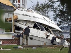 An insurance adjuster looks over a storm beached yacht off of East Front Street in New Bern, N.C., Thursday, Sept. 20, 2018. Hurricane Florence brought damaging winds and destructive flooding to the neighborhood fronting the Neuse River. (Gray Whitley/Sun Journal via AP)