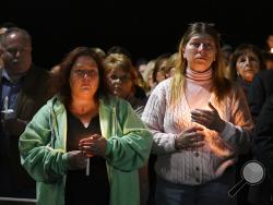 Maria Busch ,left, and Tammy Smith both of Amsterdam, N.Y., gather with family and friends for a candlelight vigil memorial at Mohawk Valley Gateway Overlook Pedestrian Bridge in Amsterdam, N.Y., Monday, Oct. 8, 2018. The memorial honored 20 people who died in Saturday's fatal limousine crash in Schoharie, N.Y., (AP Photo/Hans Pennink)