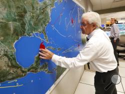 National Oceanic and Atmospheric Administration public affairs officer Dennis Feltgen updates the progress of Hurricane Michael on a large map, Tuesday, Oct. 9, 2018, at the Hurricane Center in Miami. At least 120,000 people along the Florida Panhandle were ordered to clear out Tuesday as Hurricane Michael rapidly picked up steam in the Gulf of Mexico and closed in with winds of 110 mph (175 kph) and a potential storm surge of 12 feet (3.7 meters). (AP Photo/Wilfredo Lee)