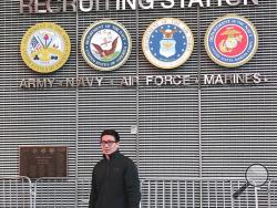 This November 2017 photo provided by Badamsereejid Gansukh shows him in front of a U.S. military recruiting office in New York's Times Square. Gansukh, whose recruiter told him his Turkish language skills would be an asset to the military, said he didn’t know he was discharged at all until he asked his congressman’s office in the summer of 2018 to help him figure out why his security screening was taking so long. (Courtesy of Badamsereejid Gansukh via AP)