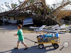 Anthony Weldon, 11, pulls a cart with his family's belongings as they relocate from their uninhabitable damaged home to stay at their landlord's place in the aftermath of Hurricane Michael in Springfield, Fla., Monday, Oct. 15, 2018. (AP Photo/David Goldman)