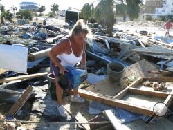 In this Oct. 14, 2018 photo Dena Frost salvages an unbroken clay pot from the wreckage of her pottery business in Mexico Beach, Fla. For decades, the town has persisted as a stubbornly middlebrow enclave on what residents proudly refer to as Florida's "Forgotten Coast." Businesses are locally owned. While some locals owned posh homes that overlooked the beach on stilts, many lived in mobile homes. (AP Photo/Russ Bynum)
