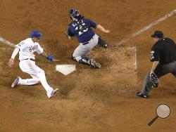 Los Angeles Dodgers' Manny Machado scores past Milwaukee Brewers catcher Erik Kratz during the 13th inning of Game 4 of the National League Championship Series baseball game Tuesday, Oct. 16, 2018, in Los Angeles. The Dodgers won 2-1 to tie the series at 2-2. (AP Photo/Mark J. Terrill)
