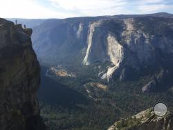 FILE - In this Sept. 27, 2018 file photo a wedding couple are seen being photographed at Taft Point in California's Yosemite National Park. A Yosemite National Park official says two visitors have died in a fall from the popular overlook. Park rangers are trying to recover the bodies of a man and a woman Thursday, Oct.25, 2018. He didn't say when the couple fell from Taft Point, which is at an elevation of 7,500 feet. Gediman says the deaths are being investigated and offered no other information. (AP Photo