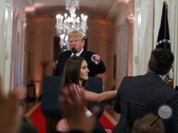 President Donald Trump watches as a White House aide reaches to take away a microphone from CNN journalist Jim Acosta during a news conference in the East Room of the White House, Wednesday, Nov. 7, 2018, in Washington. (AP Photo/Evan Vucci)