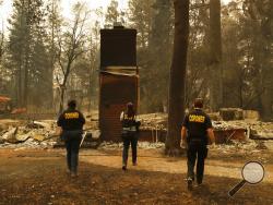 Members of the Sacramento County Coroner's office look for human remains in the rubble of a house burned at the Camp Fire, Monday, Nov. 12, 2018, in Paradise, Calif. (AP Photo/John Locher)