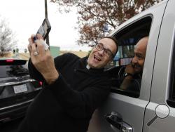 In this Wednesday, Dec. 5, 2018 photo, Father Jim Sichko, center, takes a selfie with a man after paying for his lunch at an In-N-Out Burger in the Hollywood section of Los Angeles. "My approach is not so much speaking about the word of God, although I do a lot of that, but showing the presence of God through acts of kindness that kind of shock the individual and kind of cause them to, maybe cause them to. stop for a little bit," he said. (AP Photo/Jae C. Hong)