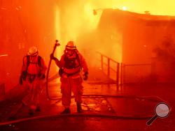 FILE - In this Thursday, Nov. 8, 2018 file photo, firefighters battle the Camp Fire as it tears through Paradise, Calif. A report on firefighter injuries in a deadly Northern California wildfire details harrowing conditions they faced and a few close calls with death. The report released Thursday, Dec. 13, 2018 by the California Department of Forestry and Fire Protection said the Camp Fire overtook three firefighters trying to set a backfire Nov. 8 to stop the blaze. (AP Photo/Noah Berger, File)