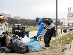The Capitol building is visible as a man who declined to give his name picks up garbage and stacks it near a trash can during a partial government shutdown on the National Mall in Washington, Tuesday, Dec. 25, 2018. (AP Photo/Andrew Harnik)