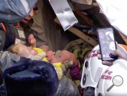 This photo provided by the Russian Emergency Situations Ministry taken from tv footage shows Emergency Situations employees save a 10 month old baby at the scene of a collapsed section of an apartment building, in Magnitigorsk, a city of 400,000 about 1,400 kilometers (870 miles) southeast of Moscow, Russia, Tuesday, Jan. 1, 2019. Rescue crews on Tuesday temporarily halted their search through the rubble in the city of Magnitogorsk while workers tried to remove or stabilize sections of the building in dange