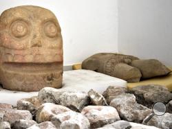 In this 2018 photo provided by Mexico's National Institute of Anthropology and History, INAH, a skull-like stone carving and a stone trunk depicting the Flayed Lord, a pre-Hispanic fertility god depicted as a skinned human corpse, are stored after being excavated from the Ndachjian–Tehuacan archaeological site in Tehuacan, Puebla state, where archaeologists have discovered the first temple dedicated to the deity. Although depictions of the god, Xipe Totec, had been found before in other cultures, a whole te