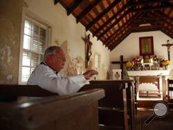 In this Jan. 8, 2019, photo, father Roy Snipes, pastor of the La Lomita Chapel, speaks during an Associated Press interview inside the sanctuary of the church in Mission, Texas. Snipes, who is a member of the Missionary Oblates of Mary Immaculate, and the Catholic Diocese worry that the federal government will seize land on the church grounds to build additional border fence and walls. (AP Photo/John L. Mone)